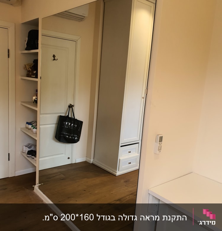 מראה גדולה על קיר בחדר עם רצפת עץ